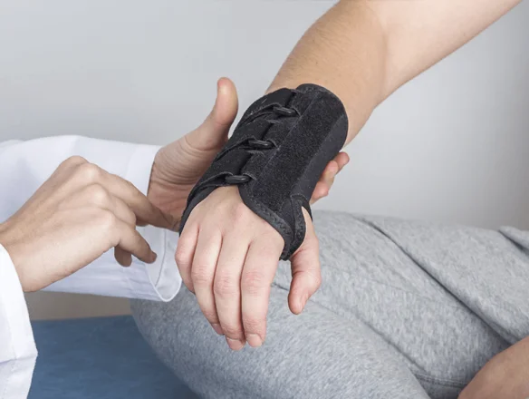 Doctor putting carpal tunnel wrist brace on patient
