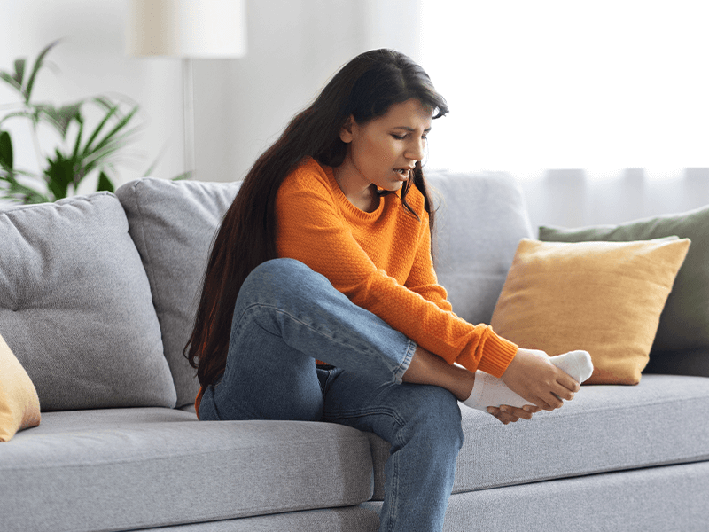 Woman sitting on couch with foot pain