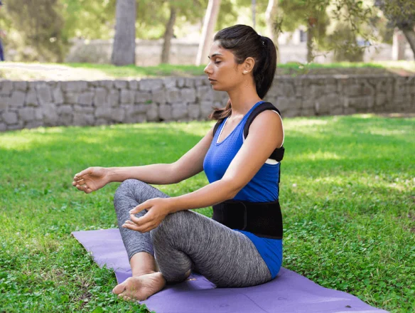 Woman sitting on mat with posture corrector