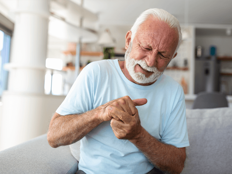 man sitting down with stiff fingers in the morning