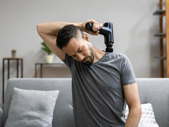 man using massage gun for shoulder pain