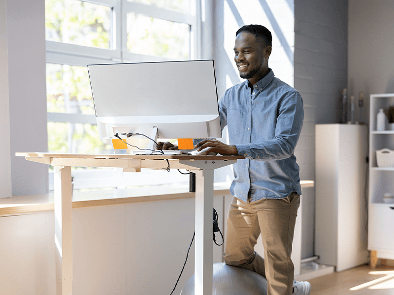 man working on computer using standing desk for back pain