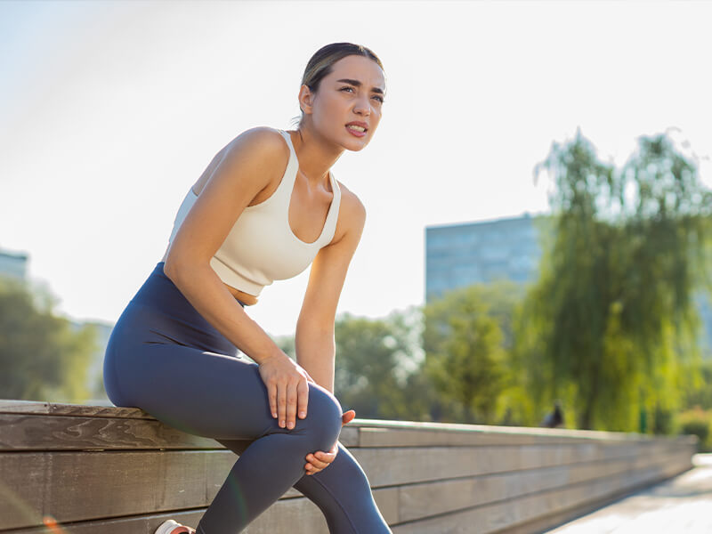 woman with joint pain stretching outdoors