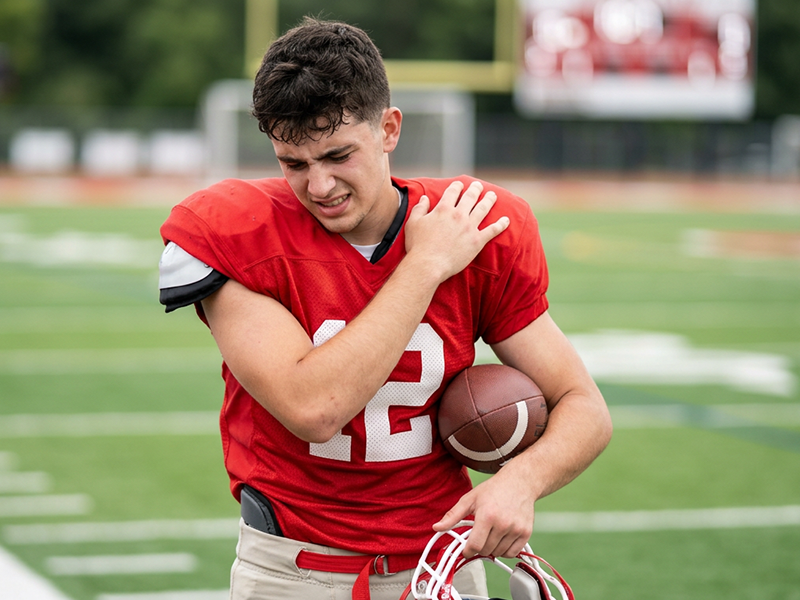 youth football player holding his shoulder after injury during a game