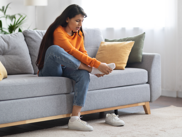 woman sitting on a couch holding her foot in pain